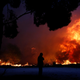 A man looks at the flames of a wildfire in Rafina.